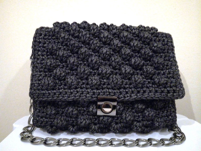 May include: A black crocheted clutch bag with a silver chain strap and a silver clasp.