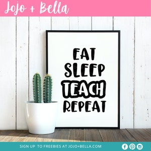 May include: Black and white printable wall art with the text "Eat Sleep Teach Repeat" in a bold, playful font. The art is framed and displayed on a white wood wall with a potted cactus in front of it.