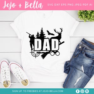 May include: White t-shirt with a black graphic design featuring the word "DAD" with hunting-themed elements. The design includes a hunter, trees, a deer, an eagle, a target, and binoculars. The shirt is paired with blue jeans and white sneakers.