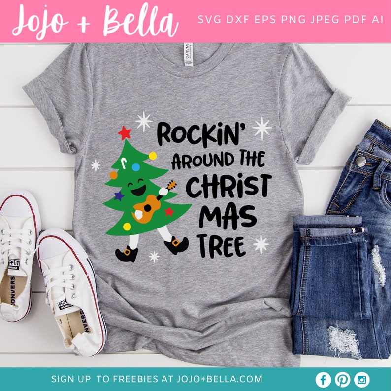Puede incluir: Una camiseta gris con un dise&ntilde;o de &aacute;rbol de Navidad. El &aacute;rbol es verde y tiene una cara sonriente. Est&aacute; tocando una guitarra y el texto "Rockin' Around The Christ Mas Tree" est&aacute; impreso en la camiseta.