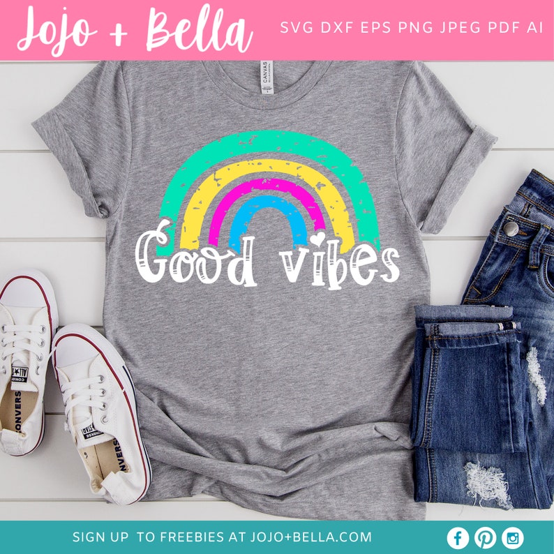 Op de afbeelding: Een grijs T-shirt met een regenboogontwerp en de tekst "Good vibes" in wit. De regenboog is gemaakt van gele, roze, blauwe en groene strepen.