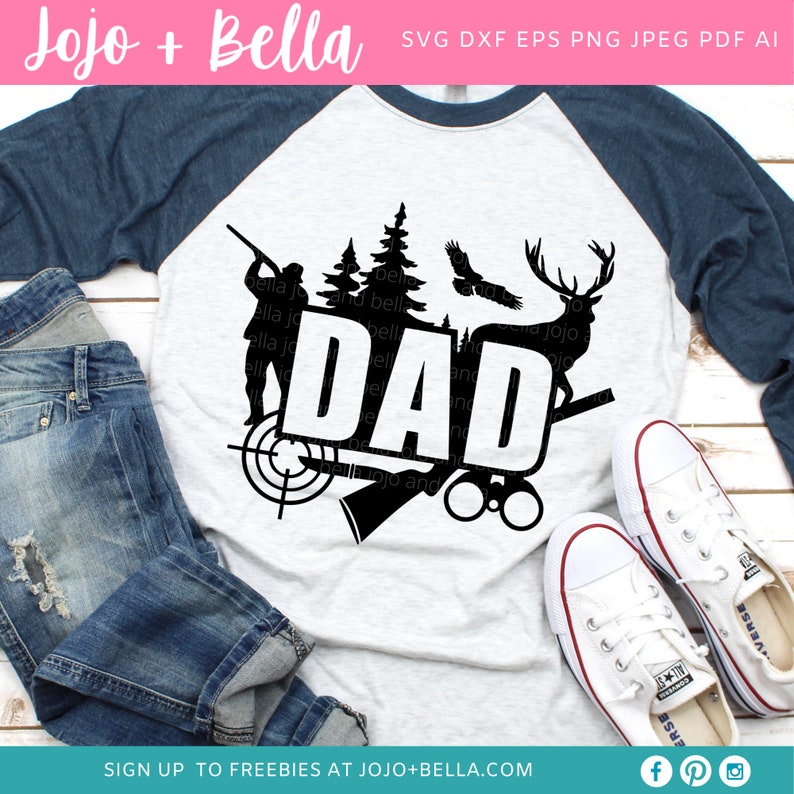 May include: A gray and navy blue raglan shirt with a black graphic design. The design includes the word "DAD" with hunting-themed illustrations such as a deer, trees, and a hunter. White sneakers and blue jeans are also in the image.