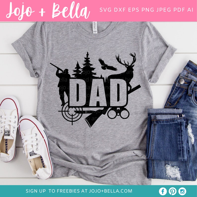 May include: A gray t-shirt with a black graphic design featuring the word "DAD" with hunting-themed imagery. The design includes a hunter, trees, a deer, and a target. White sneakers and blue jeans are also visible.