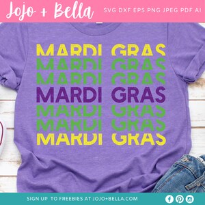 May include: Purple t-shirt with the text "Mardi Gras" repeated six times in green and yellow lettering. The text is stacked vertically and has a distressed, vintage look.