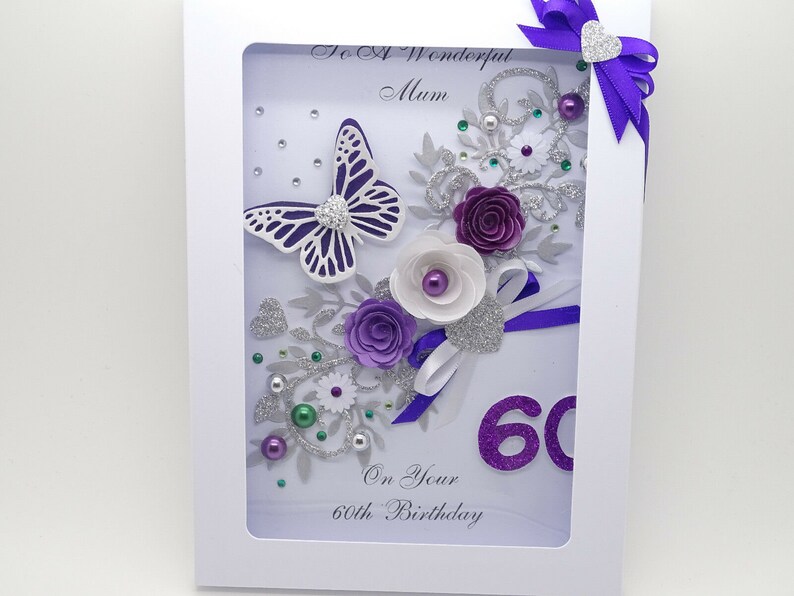 May include: A handmade card with a white background and a purple butterfly, flowers, and glitter. The card says "To A Wonderful Mum" and "On Your 60th Birthday".
