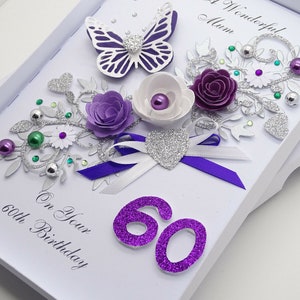 May include: A white card with a purple and silver floral design, a butterfly, and the number 60 in purple glitter. The card reads "To a Wonderful Mum" and "On Your 60th Birthday".
