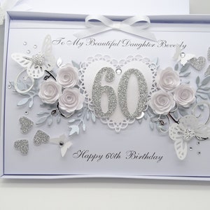 May include: A white birthday card with a decorative design. The card features the text "To My Beautiful Daughter Beverly" and "Happy 60th Birthday". Embellishments include white paper roses, butterflies, and silver glitter accents.