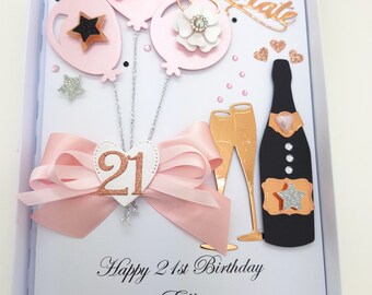 May include: A pink and white birthday card with a pink bow, balloons, champagne glasses, and a bottle of champagne. The card says "Celebrate" and "Happy 21st Birthday Ellie".
