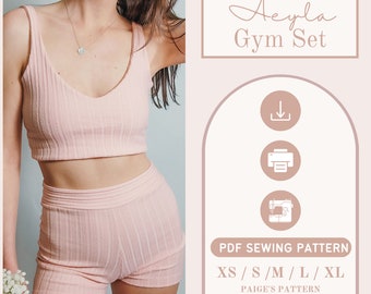 Op de afbeelding: Een naai-patroon voor een roze geribbeld crop top en bijpassende shorts. Het patroon is verkrijgbaar in de maten XS, S, M, L en XL. Het patroon heet "Aeyla Gym Set" en is een PDF-naai-patroon van Paige's Pattern.