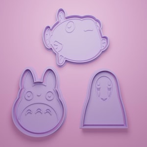 Könnte beinhalten: Drei lavendelfarbene Ausstecher in Form von Zeichentrickfiguren. Der obere ist ein Fisch, der mittlere ein Totoro-ähnliches Wesen und der untere ein Charakter mit langem Gesicht. Auf rosa Hintergrund.