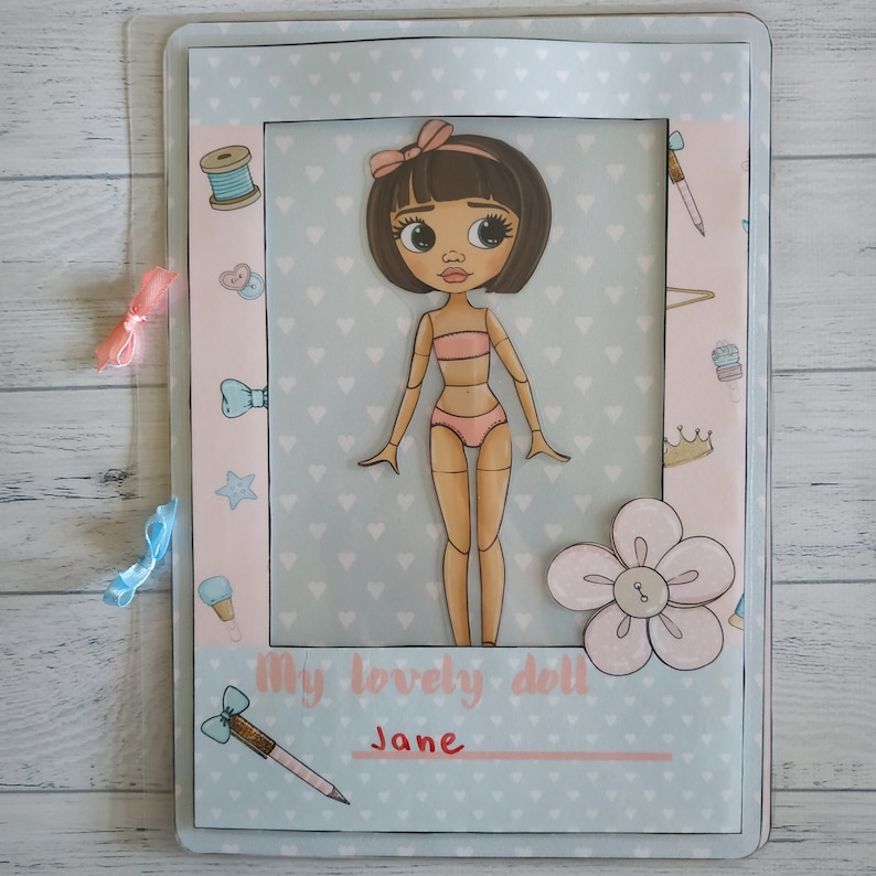 May include: A blue and pink paper doll craft kit with a girl doll, hearts, and the text "My lovely doll Jane".