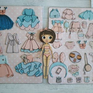 May include: A magnetic dress-up doll set with a variety of clothing options, including dresses, skirts, tops, and accessories. The doll has brown hair and big blue eyes. The set is perfect for imaginative play.