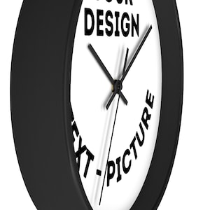 May include: A black and white clock with a black frame. The clock face has the text "YOUR DESIGN" at the top and "TEXT - PICTURE" in a circle around the clock hands.