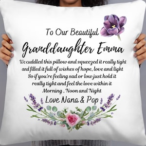 May include: White pillow with a floral design and the text "To Our Beautiful Granddaughter Emma" and "We cuddled this pillow and squeezed it really tight and filled it full of wishes of hope, love and light So if you're feeling sad or low just hold it really tight and feel the love within it Morning, Noon and Night Love Nana & Pop"