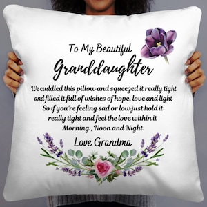 May include: White pillow with a purple flower and text that reads "To My Beautiful Granddaughter" and "We cuddled this pillow and squeezed it really tight and filled it full of wishes of hope, love and light So if you're feeling sad or low just hold it really tight and feel the love within it Morning, Noon and Night Love Grandma".