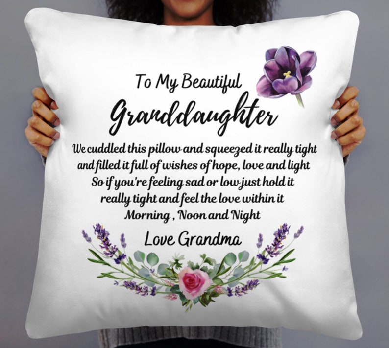 May include: White pillow with a purple flower and text that reads "To My Beautiful Granddaughter" and "We cuddled this pillow and squeezed it really tight and filled it full of wishes of hope, love and light So if you're feeling sad or low just hold it really tight and feel the love within it Morning, Noon and Night Love Grandma".
