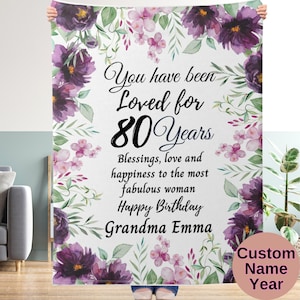 Puede incluir: Una manta blanca con estampado floral con el texto "You have been Loved for 80 Years Blessings, love and happiness to the most fabulous woman Happy Birthday Grandma Emma Custom Name Year".
