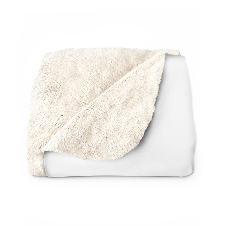 May include: A soft, white faux fur throw blanket with a white fleece backing. The blanket is folded in half and the faux fur side is facing up.