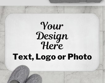 May include: White bath mat with the text "Your Design Here Text, Logo or Photo" printed in black.