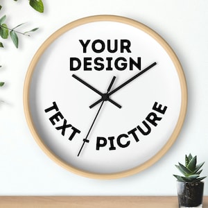 May include: A white round clock with a wood frame. The clock face has black hands and the text "YOUR DESIGN" at the top and "TEXT PICTURE" curved around the bottom.