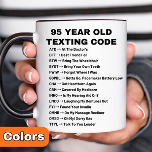 May include: White ceramic mug with a black handle and rim, featuring the text "95 YEAR OLD TEXTING CODE" in black. The mug lists humorous acronyms like "GHA → Got Heartburn Again" and "FYI → Found Your Insulin". The bottom corner shows "8 Colors".