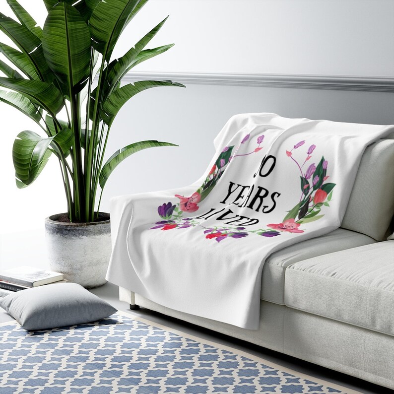 May include: White throw blanket with a floral design and the text "10 Years Lived".