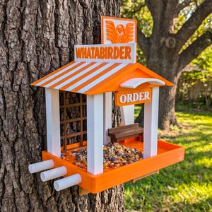 May include: A bird feeder shaped like a fast-food restaurant with an orange and white striped roof, white pillars, and a sign that reads WHATABIRDER. The structure features an ORDER sign, a small brown bench, and a tray filled with birdseed.