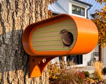 May include: A bright orange birdhouse with a rounded, elongated shape mounted to a tree trunk. The front panel features horizontal light green stripes and a circular opening where a small brown and white bird is perched looking outward.