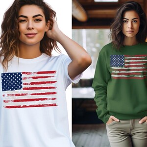May include: White t-shirt and green sweatshirt featuring a distressed American flag design. The flag has a blue square with white stars and red and white stripes. The t-shirt is short-sleeved, and the sweatshirt is long-sleeved.