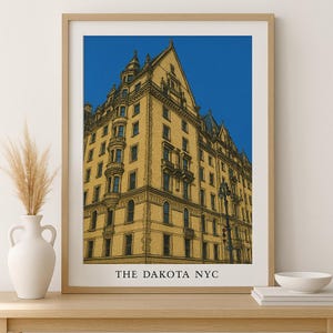 Può includere: Stampa incorniciata con un'illustrazione dettagliata del Dakota a New York, su uno sfondo blu acceso. L'edificio è raffigurato in tonalità giallo e marrone, con la scritta "THE DAKOTA NYC" in basso.