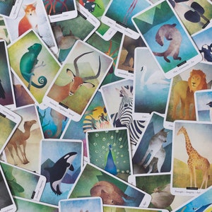 Puede incluir: Un juego de cartas de or&aacute;culo de animales coloridas con ilustraciones de varios animales, incluyendo un pavo real, una jirafa, una cebra, una mariposa, un cuervo, un camale&oacute;n y un camello. Las cartas est&aacute;n dispuestas en un patr&oacute;n aleatorio, con algunas superpuestas.