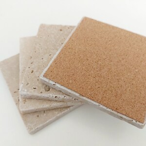 Op de afbeelding: Set van vier beige onderzetters met kurken achterkant. De onderzetters zijn gemaakt van een getextureerd materiaal en hebben een licht ruw oppervlak.