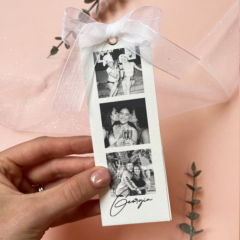 Bookmark style photo card strip in black and white. Features 3 personalised photos and name on the front. The back says will you be my bridesmaid or maid of honour.Tied with a white organa bow.