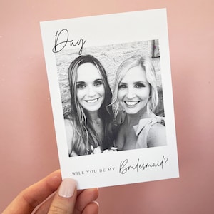 May include: A black and white photo of two women smiling. The text "Day" is at the top of the card and the text "Will you be my Bridesmaid?" is at the bottom.
