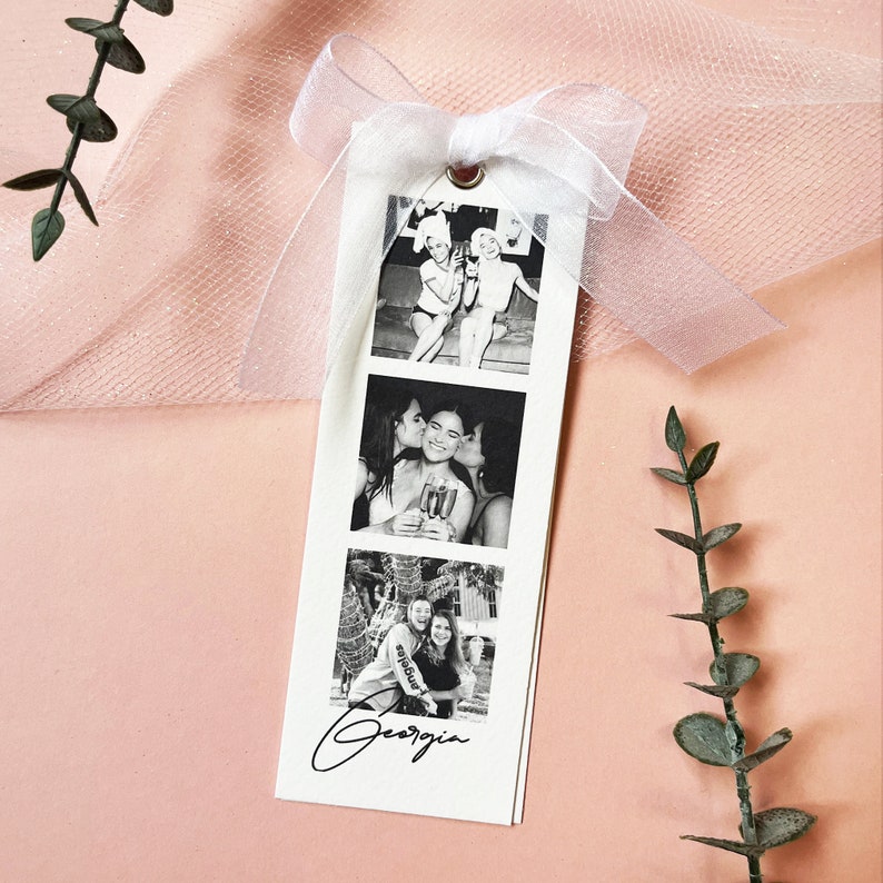 Bookmark style photo card strip in black and white. Features 3 personalised photos and name on the front. The back says will you be my bridesmaid or maid of honour.Tied with a white organa bow.