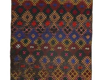 May include: A colorful rug with a geometric pattern in shades of red, blue, yellow, and black. The rug has a fringe border.