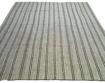 May include: A gray and white striped rug with a woven texture.