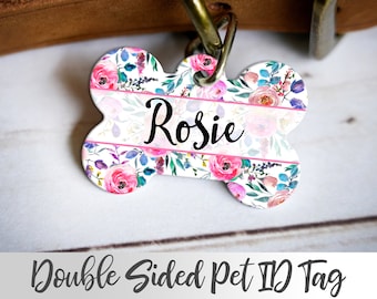 May include: A bone-shaped pet ID tag with a floral pattern in shades of pink, blue, and green. The tag has a white background and a pink stripe with the name "Rosie" written in black cursive.