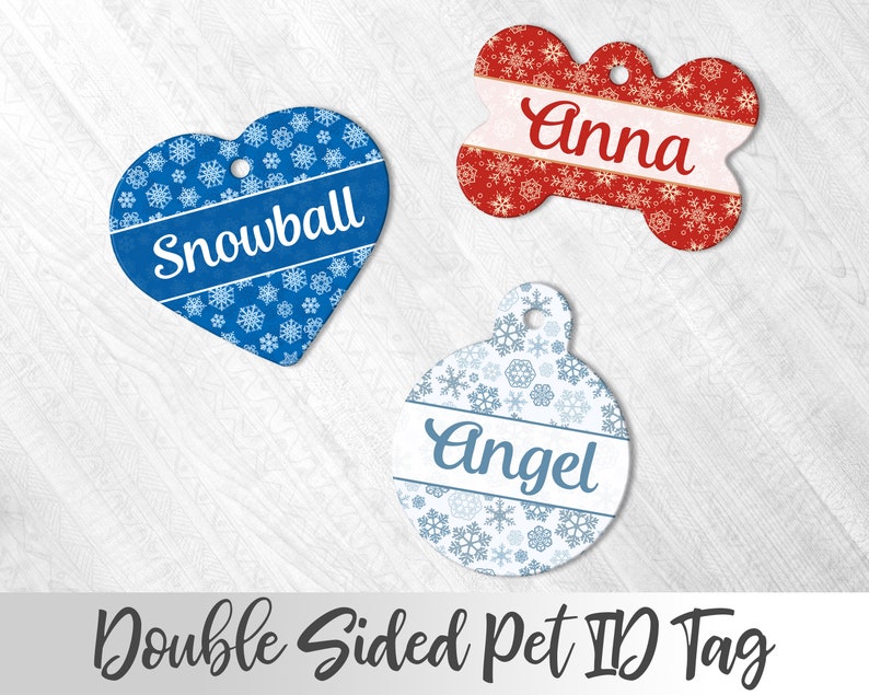 May include: Three double-sided pet ID tags with snowflake patterns. The tags are shaped like a heart, a bone, and a circle. The heart tag is blue with the name "Snowball" on it. The bone tag is red with the name "Anna" on it. The circle tag is white with the name "Angel" on it.