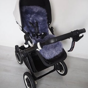 May include: A black stroller with a gray faux fur liner. The stroller has a white canopy and black wheels.