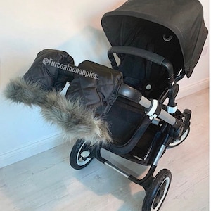 May include: Black stroller with a black quilted handle muff with faux fur trim. The stroller has a black canopy and black wheels. The text '@Furcoatnonappies_' is visible on the handle muff.