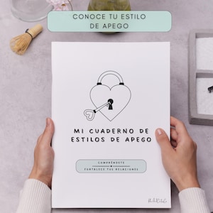 A white notebook with the text "MI CUADERNO DE ESTILOS DE APEGO" and the phrases "CONOCE TU ESTILO DE APEGO" and "COMPRENDETE FORTALECE TUS RELACIONES". The cover features a heart-shaped lock and key design.