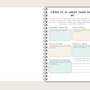 A spiral-bound notebook with a white cover and pages. The right page features text in Spanish, including the title "CÓMO ES EL AMOR SANO PARA MÍ" and several sections for reflection on healthy love, with prompts and space for writing.