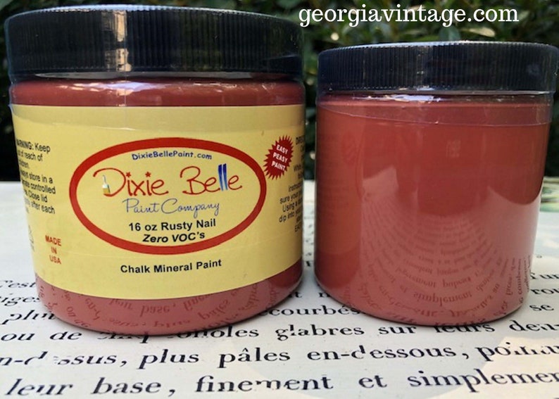 K&ouml;nnte beinhalten: Ein 473 ml Glas Dixie Belle Chalk Mineral Paint in der Farbe Rusty Nail. Die Farbe ist VOC-frei und einfach zu verwenden. Das Glas ist mit dem Dixie Belle Logo und der Website-Adresse beschriftet.