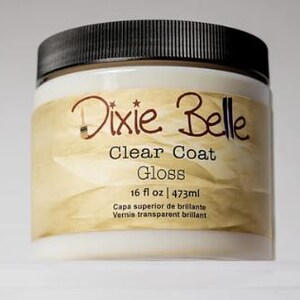 Może przedstawiać: Okrągły plastikowy pojemnik z czarną zakrętką zawierający lakier Dixie Belle Clear Coat Gloss. Beżowa etykieta zawiera nazwę marki, rodzaj produktu oraz objętość 473 ml wydrukowaną czarnym tekstem na teksturowanym tle.