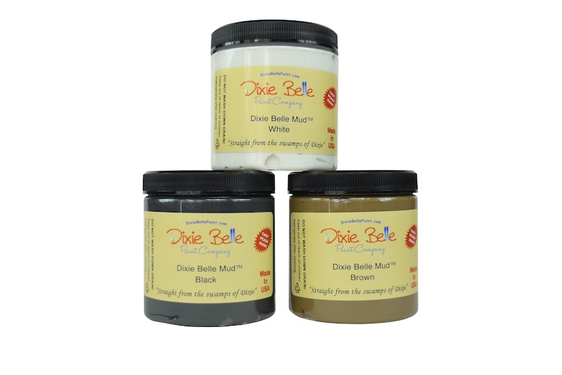May include: Three jars of Dixie Belle Mud paint in white, black, and brown. The jars are labeled with the Dixie Belle Paint Company logo and the color of the paint. The text on the jars reads "Dixie Belle Mud&trade;" and "Straight from the swamps of Dixie".