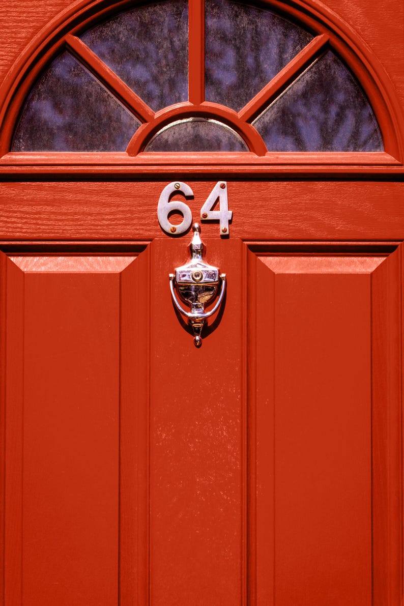 K&ouml;nnte beinhalten: Eine rote Haust&uuml;r mit einem silbernen T&uuml;rklopfer und der Nummer 64 darauf.