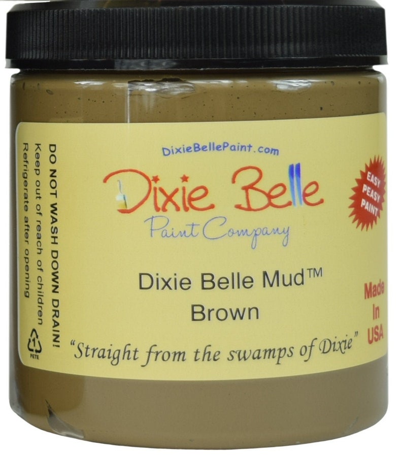 May include: A glass jar of Dixie Belle Mud Brown paint. The jar has a yellow label with the company logo and the text "Dixie Belle Mud TM Brown" and "Straight from the swamps of Dixie".