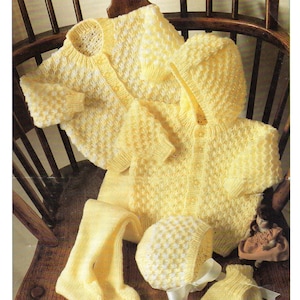 以下が含まれることがあります： 黄色と白のニットのベビー服。カーディガン、帽子、ミトン、レギンスが含まれています。