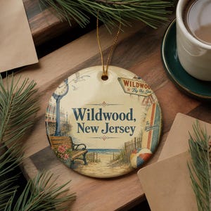A decorative ornament with a beach scene and the text "Wildwood, New Jersey" is displayed on a wooden surface, accompanied by a cup of coffee and pine branches.